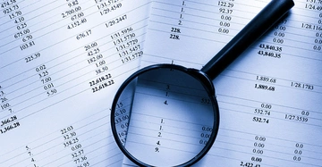 Lupe vergrößert Tabellenwerte auf Finanzdokumenten in einem Büro setting.
