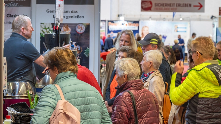 Galerie-Bild 1: eine Gruppe älterer Menschen vor einem Messestand
