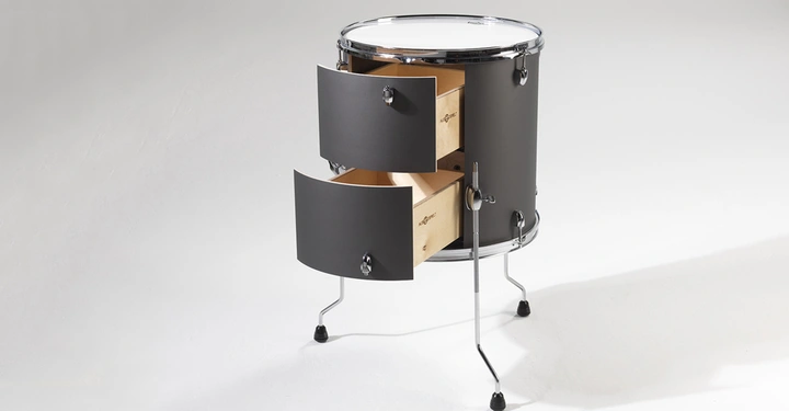 Eine Trommel mit zwei offenen Schubladen steht auf drei Beinen in einem leeren Raum