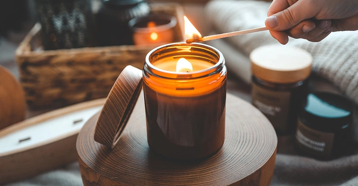 Eine Frau zündet eine Duftkerze an. Herbstduft für das Zuhause.