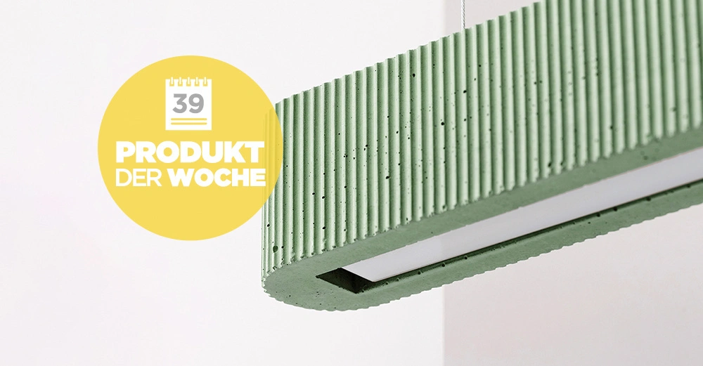 Eine grüne, geriffelte Hängelampe hängt im weißen Raum. Ein gelber Kreis links enthält die Aufschrift 39 PRODUKT DER WOCHE.