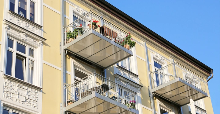 Galerie-Bild 3: Metallene Anbaubalkone an einem zitronengelben Altbau, Stuckverzierungen um die Fenster