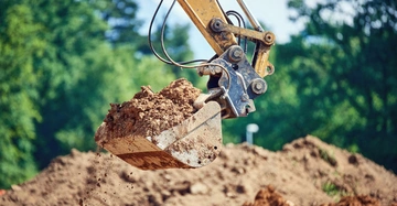 Gelber Bagger befördert Erde auf der Baustelle.
