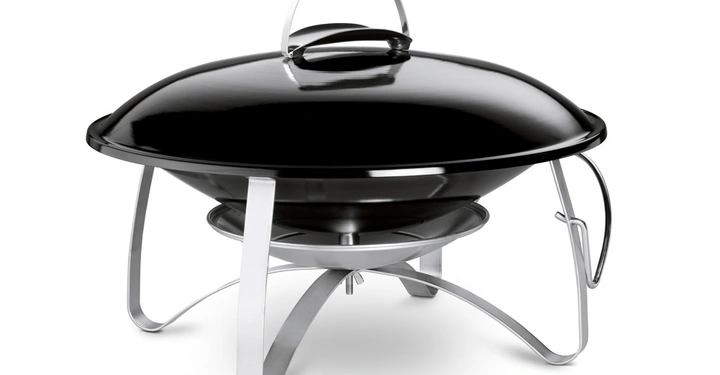 Galerie-Bild 12: Schwarzer tragbarer Grill steht auf silbernen Metallbeinen Raum ist hell und Grillabdeckung hat einen Griff oben