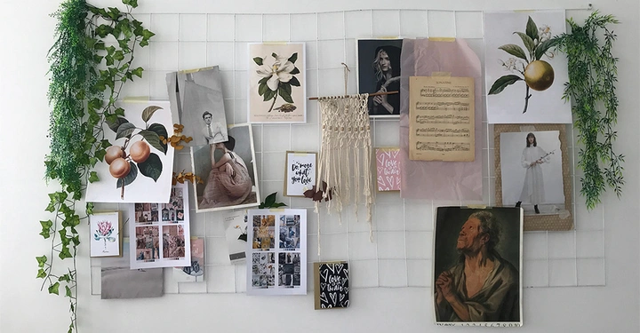 Weiße Gitterwand mit aufgehängten Bildern und Drucken. Enthält Pflanzenillustrationen Menschenporträts Kunstwerke und Kalligrafie. Grüne künstliche Pflanze an den Seiten. Text 1: "Do more of what you love" Text 2: "love lives here"