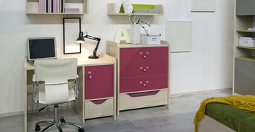 Schreibtisch mit einem Laptop steht neben einem mehrfarbigen Schrank darin Schubladen und Fächer Enthalten Ein Drehstuhl daneben In einem modernen Zimmer mit Regal und Dekorationen an der Wand