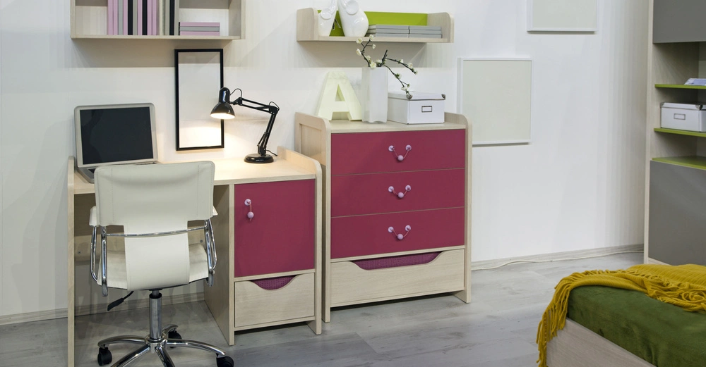 Schreibtisch mit einem Laptop steht neben einem mehrfarbigen Schrank darin Schubladen und Fächer Enthalten Ein Drehstuhl daneben In einem modernen Zimmer mit Regal und Dekorationen an der Wand