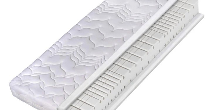 Eine weiße Matratze mit einem strukturierten Muster wird zur Seite geklappt um den inneren Schaumstoff mit vertikalen und horizontalen Einschnitten zu zeigen. Der Hintergrund ist weiß.