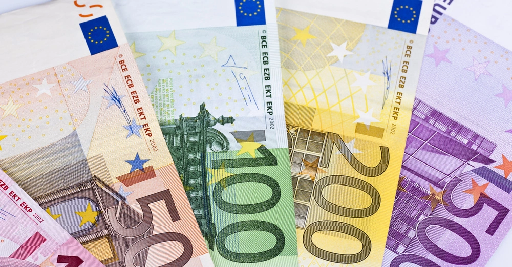 Bunte Euro-Banknoten liegen fächerförmig nebeneinander auf einer hellen Oberfläche. Links beginnt es mit 10 Euro, gefolgt von 50 Euro, 100 Euro, 200 Euro und 500 Euro.