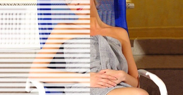 Frau sitzt in einem Stuhl und trägt ein graues Handtuch ein Schattenmuster fällt auf ihr Gesicht Umgebung zeigt eine gelbe Wand und eine Treppe