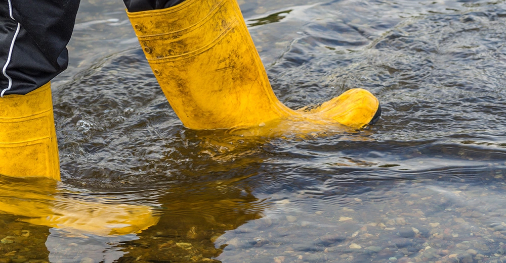 Gelbe Gummistiefel waten durch Hochwasser