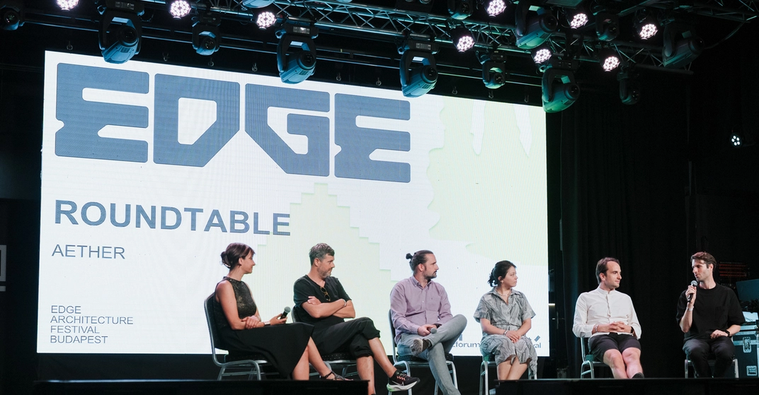 Eine Gruppe Architektinnen und Architekten sitzen bei dem Edge-Festival 2025 auf einer Bühne. Hinter ihnen ist eine Leinwand, auf der das Logo des Festivals zu sehen ist.