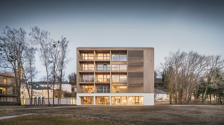 Galerie-Bild 5: Frontalaufnahme im Dämmerlicht von wunderschönem großem Holzbau mit erleuchteten Fenstern