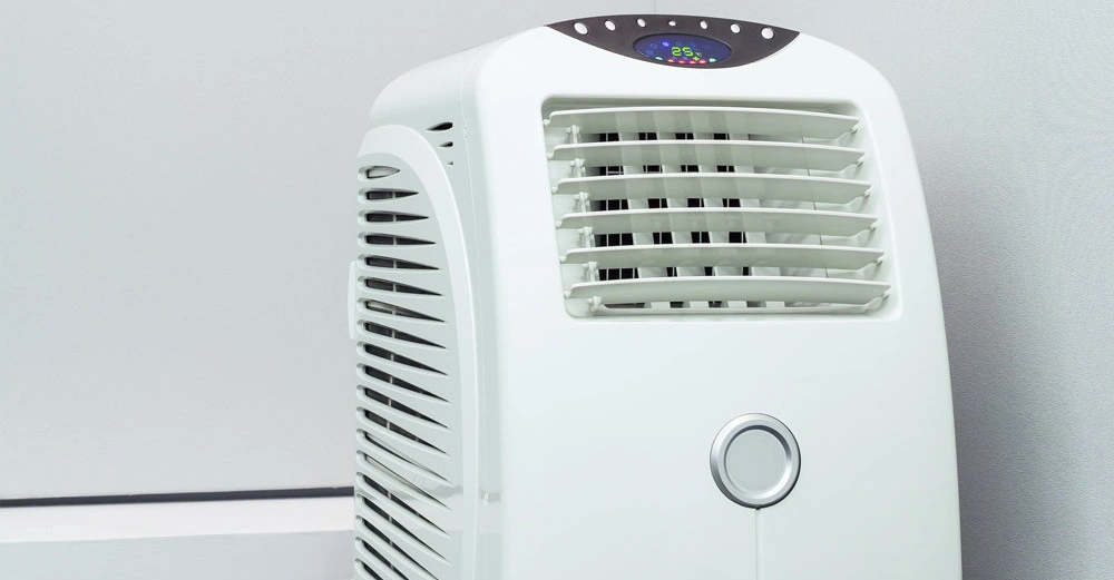 Ein weißer tragbarer Luftkühler funktioniert im Innenraum; das Display zeigt 25 an, umgeben von einer grauen Wand und einem weißen Boden.