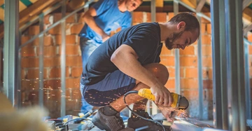 Zwei Spengler arbeiten an den Metallkomponenten eines Dachs, Funken sprühen.