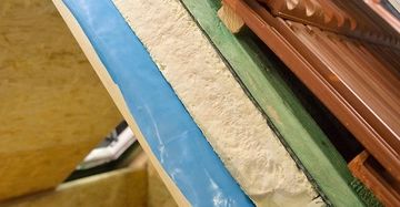 Querschnitt eines Steildaches mit Dampfbremse, Dämmung, Lattung, Hohlraum und klassischen Dachziegeln