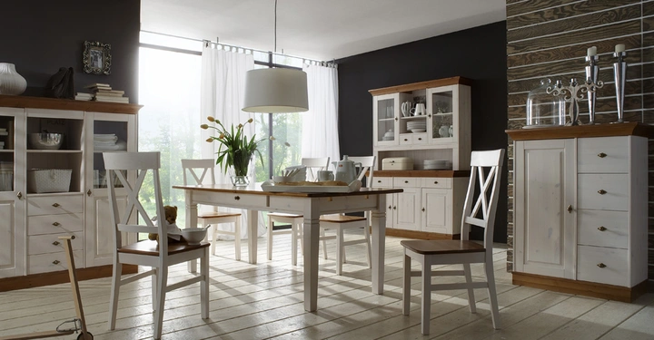 Galerie-Bild 7: Ein Esstisch steht im hell erleuchteten Raum auf Holzboden umgeben von vier Stühlen mit einer Vase Blumen während Schränke und Regale mit Geschirr und Dekorationen im Hintergrund stehen.