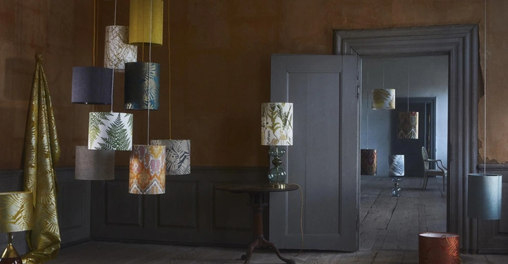 Mehrere bunte Hängeleuchten hängen an der Decke und dekorieren einen rustikalen Raum mit Holzwänden und Holzboden; im Hintergrund sind weitere Räume mit ähnlicher Dekoration sichtbar.