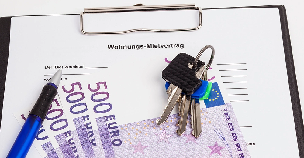 Vertrag über Mietkaution in Klemmbrett mit Hausschlüsseln darauf und vier 500-Euro Scheinen plus Kugelschreiber zum Unterzeichnen