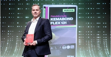 Geschäftsman in schwarzem Anzug auf Bühne mit Auszeichnung in der Hand