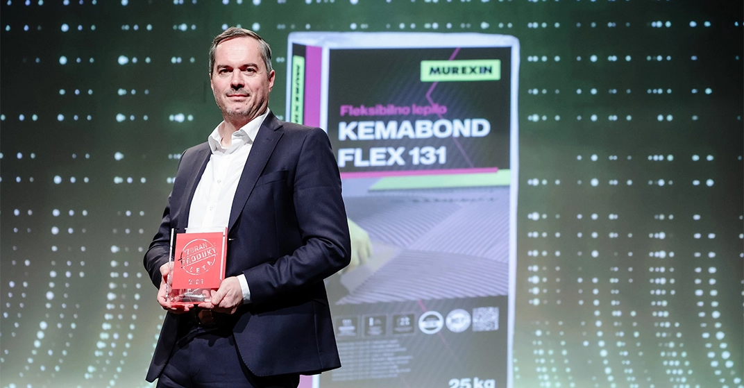 Geschäftsman in schwarzem Anzug auf Bühne mit Auszeichnung in der Hand