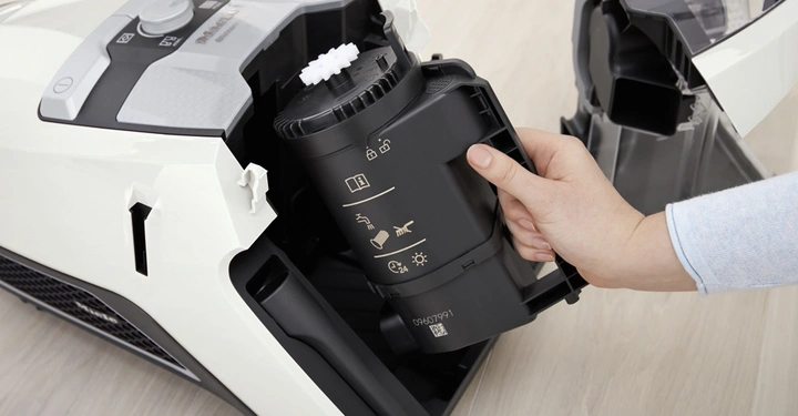 Hand entfernt Behälter aus Staubsauger in heller Umgebung.