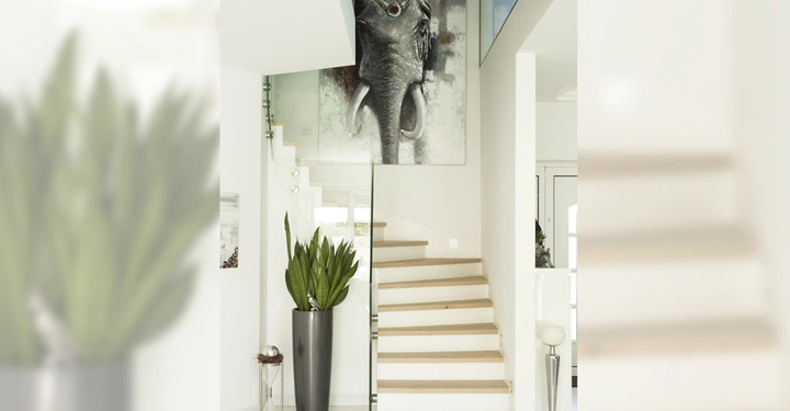 Galerie-Bild 4: Treppen steigen in einem modernen, hellen Innenraum Dekorativpflanze in der Nähe und großes Schwarz-Weiß-Gemälde eines Elefanten an der Wand Treppengeländer aus Glas