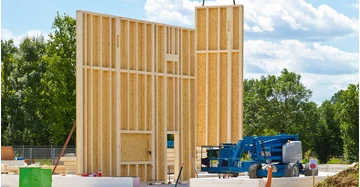vorgefertigte Hauswände in Holzrahmenbau werden auf Baustelle gebracht