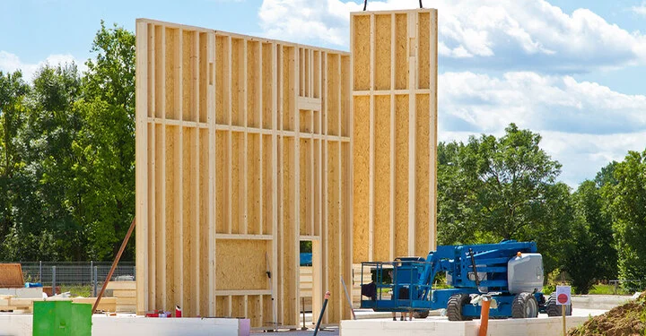 vorgefertigte Hauswände in Holzrahmenbau werden auf Baustelle gebracht