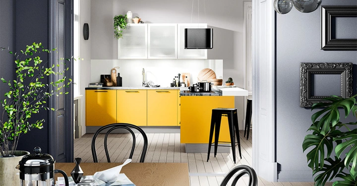 Helle Küche mit gelben Unterschränken und weißen Oberschränken eine Theke mit Barhocker Küchenutensilien und Pflanzen auf den Arbeitsflächen befindet sich neben einem Esszimmer mit Holz-Esstisch und Pflanzen.