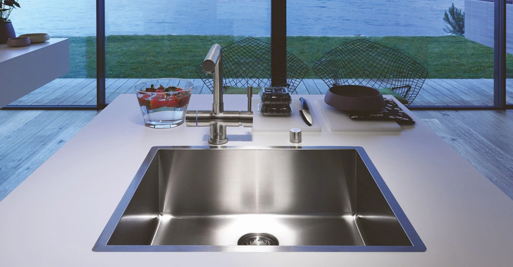 Ein Edelstahlspülbecken mit Wasserhahn in einer modernen Küche bereitet Essen vor Blick auf den Garten und den See durch große Fenster im Hintergrund