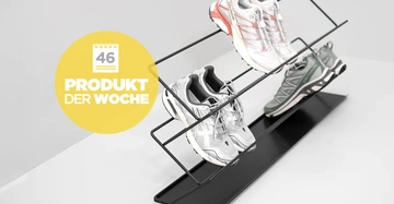 Ein schwarzes Schuhregal hält zwei Paar Sportschuhe vor einer grauen Wand Produkt der Woche Text auf gelbem Kreis mit Kalender zeigt 46