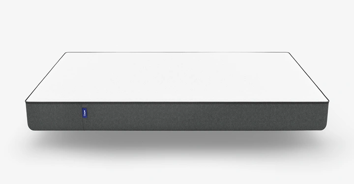 Galerie-Bild 4: Matratze schwebt in einem leeren weißen Raum. Die Matratze hat eine weiße Oberseite und einen grauen Rand mit einem blauen Etikett in der Mitte.