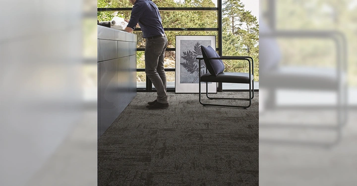 Galerie-Bild 6: Person arbeitet an einem Schreibtisch. Hintergrund: großes Fenster mit Blick auf Bäume eingerahmtes Bild schwarzer Sessel Teppichboden.