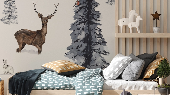 Winterlich eingebettetes Kinderbett steht vor Wand mit Waldszene und Hirsch im tiefen Schnee.
