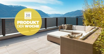 Braunes Loungesofa steht auf einer Terrasse mit Fliesenboden vor einem schwarzen Geländer. Im Hintergrund sind Berge zu sehen. In einem gelben Kreis steht 38 PRODUKT DER WOCHE.