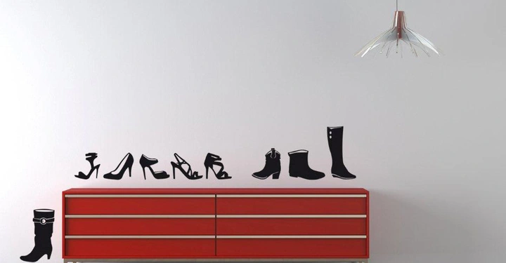 Galerie-Bild 2: Rote Kommode steht an einer weißen Wand mit schwarzen Schuh-Silhouetten darüber; Hängelampe hängt an der Decke; Blumentopf neben dem Schrank; brauner Holzbodenund minimalistischer Raum.