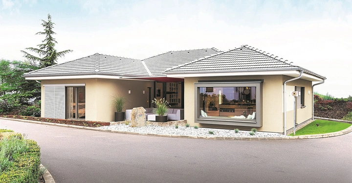 Galerie-Bild 2: Modernes einstöckiges Haus mit Flachdach große Fensterfront Terrasse mit Pflanzen und Steinen umgeben von Garten und Gehweg am Rande eines begrünten Wohngebiets bei heiterem Himmel.