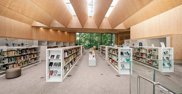 Innenaufnahme einer hellen Bibliothek aus Holz mit zahlreichen Regalen und Sitzgelegenheiten in Barcelona.