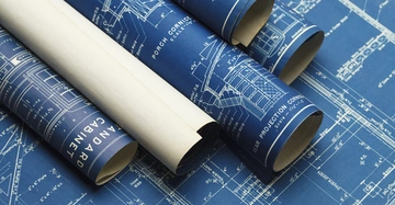 Blaupausenrollen liegen auf einem ausgebreiteten Architektenplan. Die Blaupausen zeigen detaillierte Zeichnungen und technische Angaben von Gebäuden und Komponenten. Text: Standard Cabinet Porch Cornice Rear Projection Cornice Scale 1/2 in 1 ft.