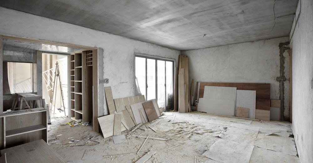 Unfertiger Raum liegend diverse Holzplatten und Baumaterialien Umgebung unfertige Wände und Holzboden mit Schmutz bedeckt große Fenster und Holzböcke mit Regalen links werkzeugfreie Szene.