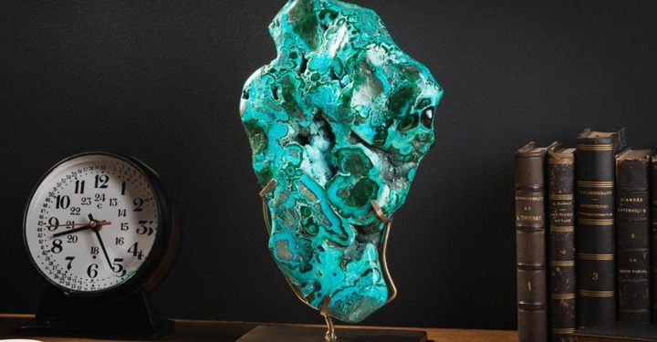 Uhr zeigt 2 Uhr 14 Minuten Steinskulptur steht auf Sockel Regale mit alten Büchern im Hintergrund schreibtischähnlicher Untergrund schwarze Wand im Hintergrund