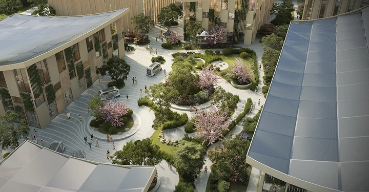 Menschen spazieren in einem modernen, begrünten Innenhof mit blühenden Bäumen und kurvigen Wegen umgeben von mehrstöckigen Gebäuden mit gläsernen Fassaden und begrünten Balkonen bei Tageslicht.