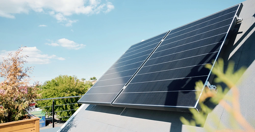 zwei große Solapaneele auf sonniger Dachterrasse mit großem hölzernen Pflanztrog, blauer Himmel