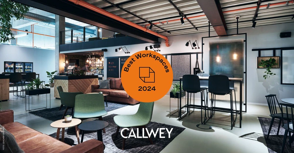 Großraumbüro mit modernen Möbeln und Pflanzen in einem Loftstil mit hohen Decken und vielen Beleuchtungselementen Im Vordergrund ist ein Award zu sehen auf dem steht Best Workspaces 2024 Callwey