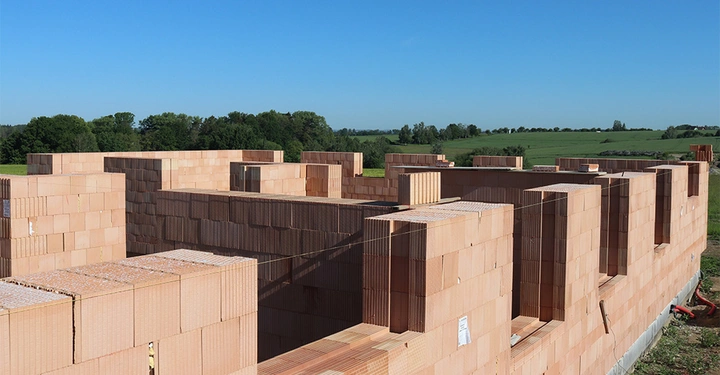 Galerie-Bild 3: Mauersteine werden gestapelt und zu einer Struktur geformt auf einem offenen Feld mit Bäumen und blauem Himmel im Hintergrund