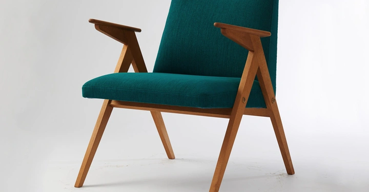 Holzstuhl mit grüner Polsterung steht in einem minimalistisch gestalteten, hellen Raum auf einem weißen Hintergrund.