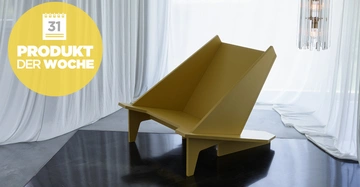 Brauner moderner Stuhl steht im Vordergrund auf einem grauen Boden in einem Raum mit weißen Vorhängen und einer Hängelampe. Links oben gelber Kreis mit Text 31 PRODUKT DER WOCHE