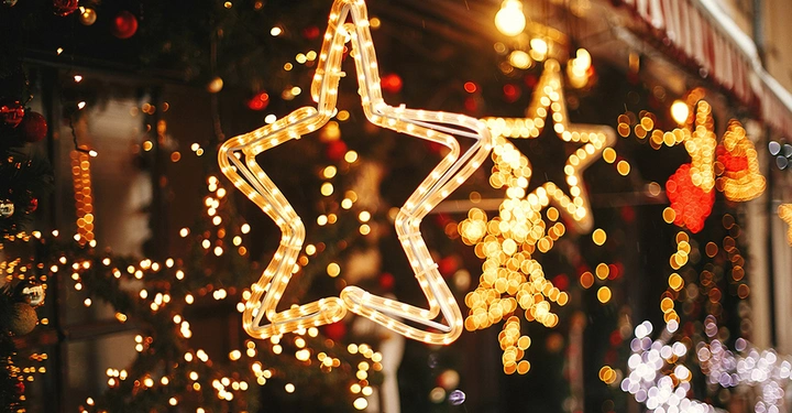 Große LED-Leuchtsterne als Weihnachtsbeleuchtung im Schaufenster mit warmweißen Lichterketten und festlichem Bokeh-Hintergrund.