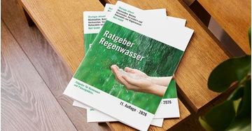 Mehrere Broschüren mit Titel Ratgeber Regenwasser liegen auf moderner Holzbank.